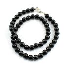 Schörl schwarzer Turmalin Stein Trommelstein Anhänger Trommelsteinanhänger Perlenkette Kugelkette Collier Buttonkette Edelstein Heilstein Halsschmuck Schmuck Schmuckstein Schmuckkette schwarze Turmalinkette Turmalinschmuck Turmalincollier schwarze Turmalinspitze